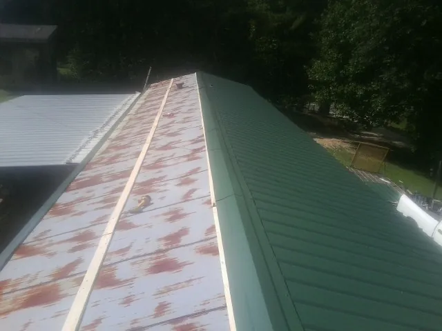 Old rusted panels beside newly installed green metal roofing — Wind Damage Roof Repair by Roofing Brothers in Mulberry