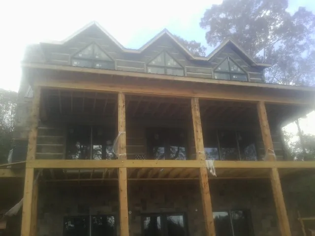 Dormers and porch framing on a large log home under construction — Roof Coating work by our crew in Mulberry