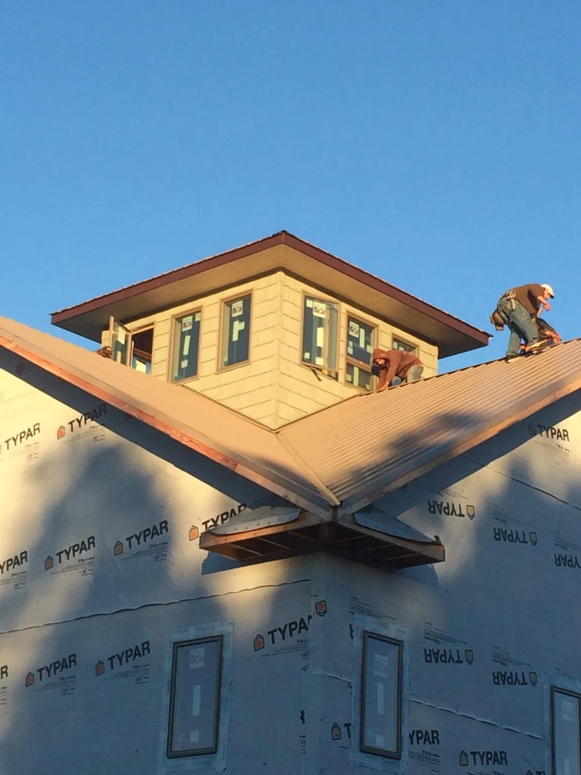 Roofers working around a rooftop cupola on a new metal roof at sunset — Roof Waterproofing in Mulberry by Roofing Brothers
